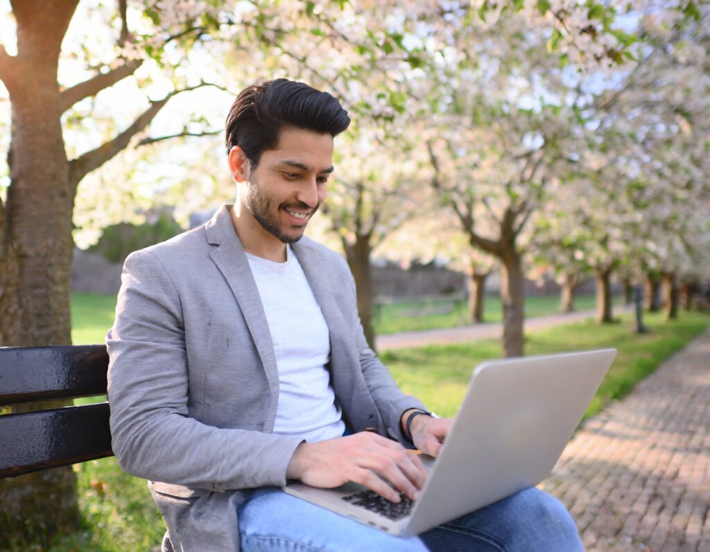 man sitting on a park bench working on laptop